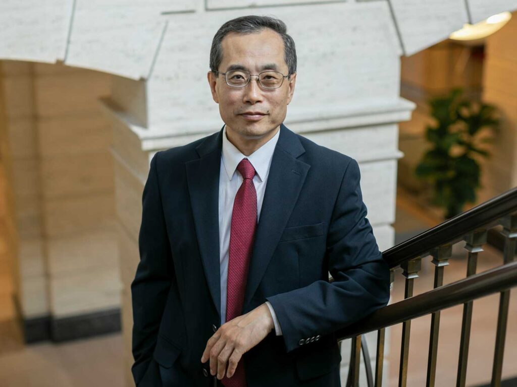 Dyson Dean Jinhua Zhao stands on the staircase in Warren Hall.